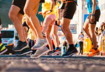 Why Your Easy Runs Are Holding Back Your Marathon Progress Close-up view of multiple runners beginning a race, showing only their legs and athletic running shoes in motion.