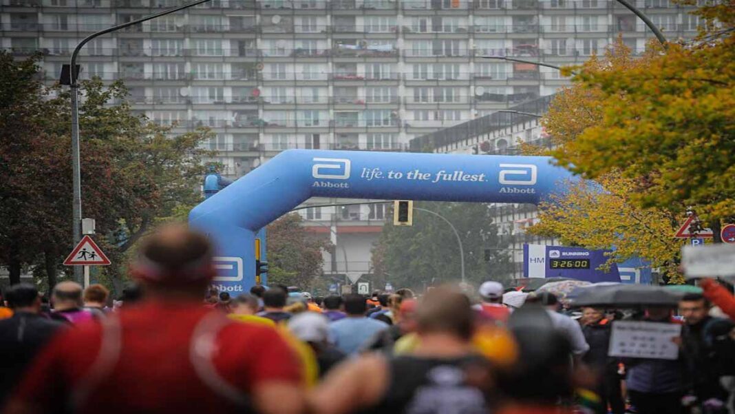 LT1 and Zone 2 Marathon Training_coachT A crowded marathon course looking from behind a sea of runners moving toward a large blue inflatable Abbott archway that reads