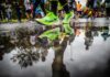Couch to 10K: A Realistic Plan for Your First 10K Neon green running shoes mid-stride beside a puddle reflecting runners at a 10K road race