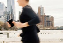 How Much Does an Online Running Coach Cost? Runner moving through a city skyline while checking her phone, representing online running coaching